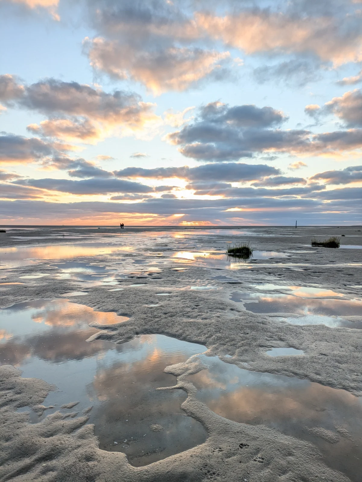 Abendhimmel spiegelt sich in Wasserflächen auf dem nassen Sand am Strand von St. Peter-Ording